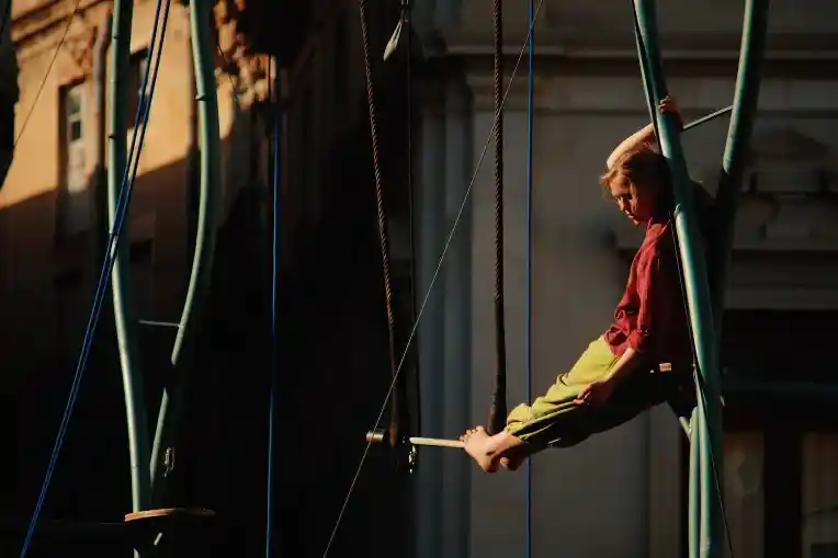 Una trapezista fent equilibris dalt de la barra del trapezi